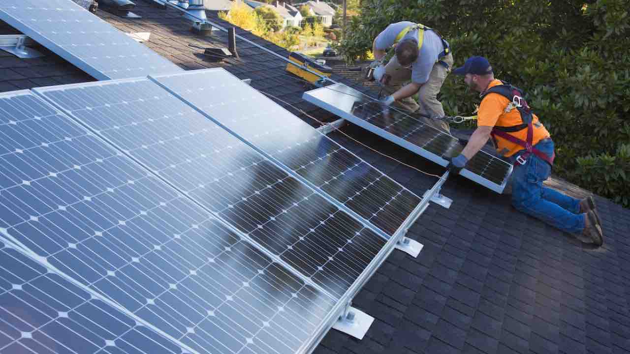 Caucasian men installing panels on roof