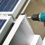 Worker with power drill installing windbreaker on solar panel construction - Downer EDI optimised