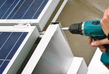 Worker with power drill installing windbreaker on solar panel construction - Downer EDI optimised