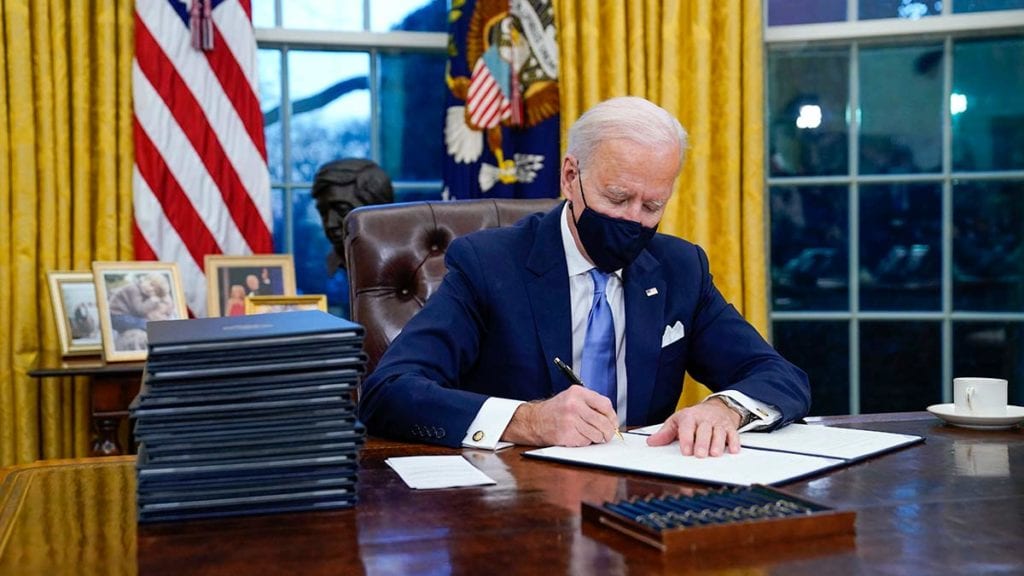 President Joe Biden signs his first executive order in the Oval Office of the White House