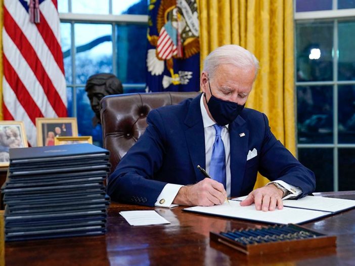 El presidente Joe Biden firma su primera orden ejecutiva en la Oficina Oval de la Casa Blanca