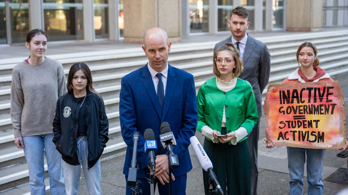 Students Laura Kirwin, Izzy Raj-Seppings, Ava Princi and Liv Heaton watch as lawyer David Barnden speaks to media outside The Federal Court of Australia in Sydney in May 2021. (AAP Image/James Gourley)