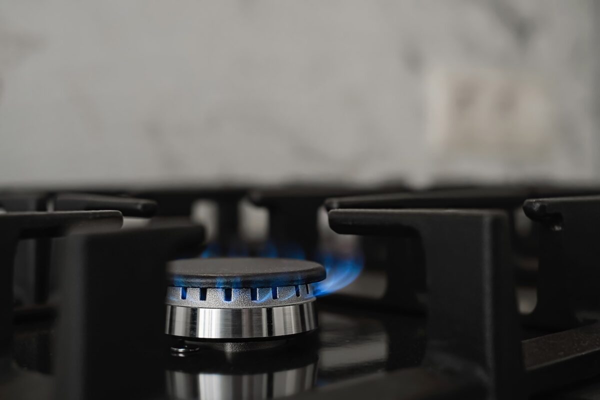 Modern kitchen stove, natural gas burns with a blue flame. Household gas consumption. Close-up, selective focus